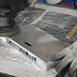 Abrasive deburring of a metal component using a handheld sander
